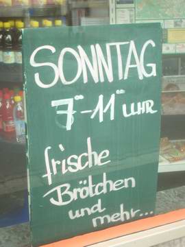 Schild im Schaufenster eines Bäckerladens: Frische Brötchen am Sonntag, 7 - 11 Uhr