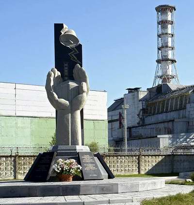 Gedenkstätte auf dem Kraftwerksgelände Tschernobyl, rechts der zerstörte Reaktorblock 4 mit dem Sarkophag 