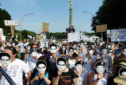 Berlin, 19. Juni 2013: Demonstration während des Berlin-Besuchs von US-Präsident Barack Obama gegen die von der NSA eingeführte Software PRISM zur Überwachung und Auswertung elektronischer Medien und elektronisch gespeicherter Daten. Demonstranten halten Fotos von Edward Snowden vor ihren Gesichtern. Im Hintergrund die Siegessäule
